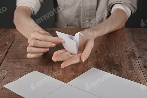 Preview: hands of an elderly woman fold origami paper. Creating an origami paper crane
