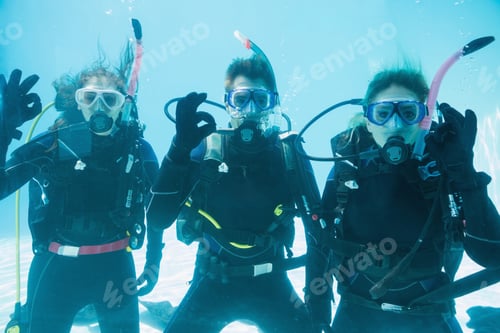 Preview: Friends On Scuba Training Submerged In Swimming Pool Looking To Camera On Their Holidays