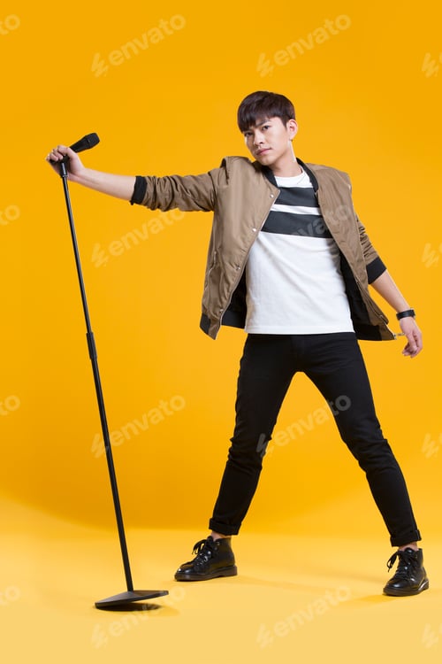 Preview: Cheerful young Chinese man singing with microphone