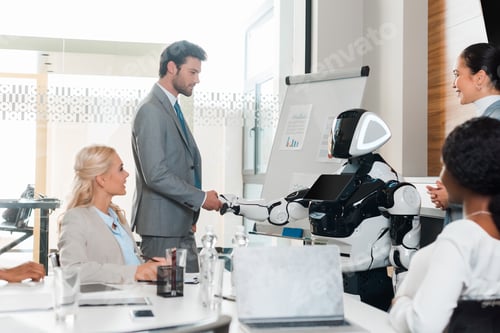 Preview: handsome businessman shaking hands with robot near multicultural colleagues sitting in conference