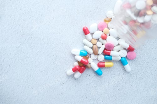 Preview: high angle view of colorful pills spilling from container