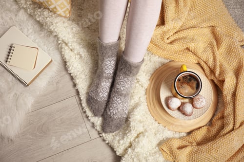 Preview: Woman and cup of hot winter drink on floor at home, above view