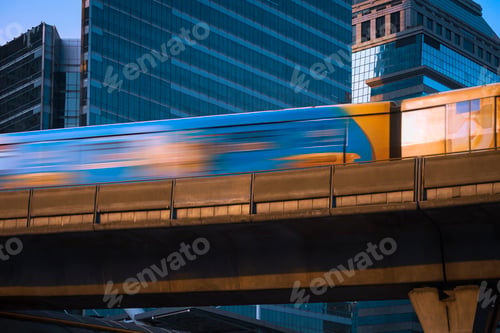 Preview: Motion blur of Sky train moving on elevated railway with glass business buildings in the city
