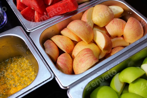 Preview: Assorted fresh fruits neatly arranged in stainless steel containers.