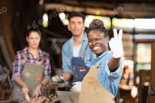 Preview: Portrait of carpenter female worker standing in front of colleague in workshop
