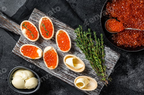 Preview: Tartlets with Red caviar, butter and thyme on wooden board. Black background. Top view