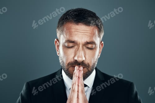 Preview: Charming young man in full suit keeping hands clasped while standing against grey background
