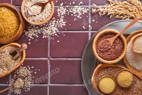 Preview: White, brown and red rice, buckwheat, millet, corn groats, quinoa and bulgur in wooden bowls on a br