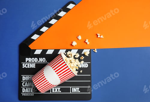 Preview: Flat lay composition with popcorn, cinema clapperboard and space for text on color background