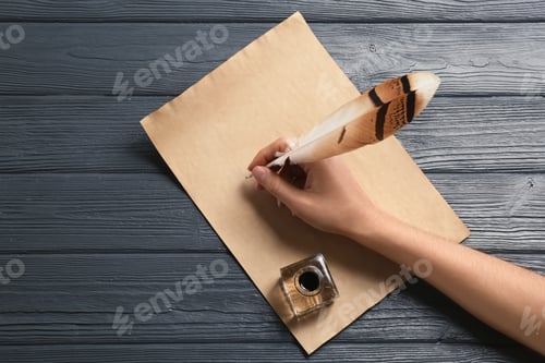 Preview: Woman using feather pen to write with ink on parchment at wooden table, top view. Space for text