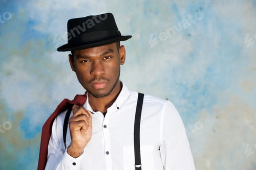 Preview: Close up cool young african american man posing with hat against wall