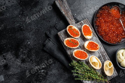 Preview: Tartlets with Red caviar, butter and thyme on wooden board. Black background. Top view. Copy space