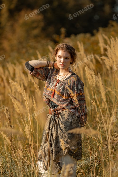 Preview: A young woman in nature. Beautiful girl in boho style clothes stands in a field of ears of corn