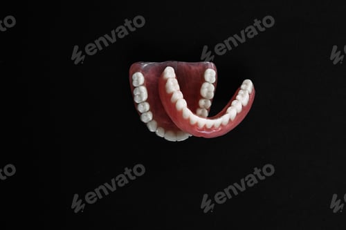 Preview: Full removable plastic denture of the jaws. A set of dentures on a black background