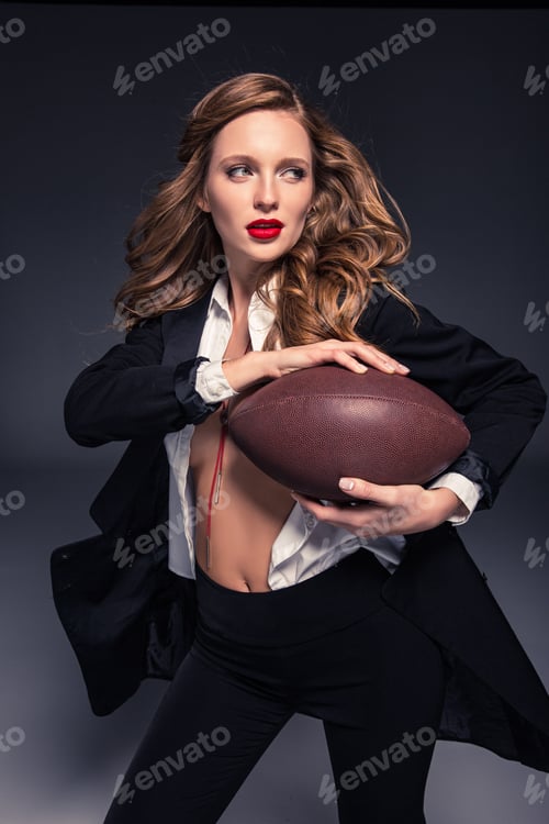 Preview: beautiful woman with long hair holding american football ball and looking away