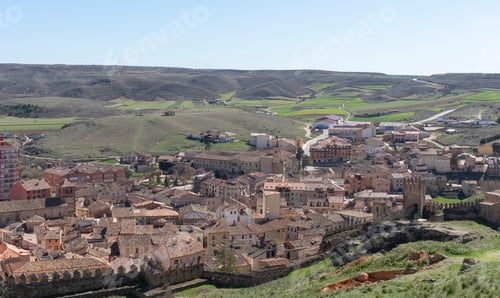 Preview: Aerial view of a historic town with medieval architecture and surrounding green hills.
