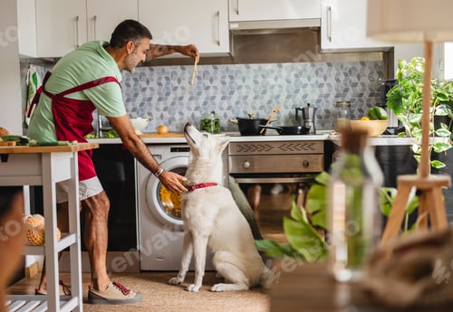 Preview: Hispanic mature man cooking with dog in kitchen feeds spaghetti