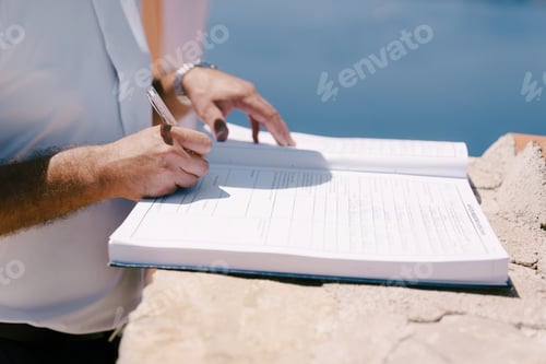 Preview: Groom signs the marriage registration book with a pen. Cropped. Faceless