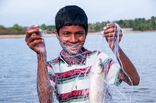 Preview: Young Fisherman take fish out of the net in front lake, India.
