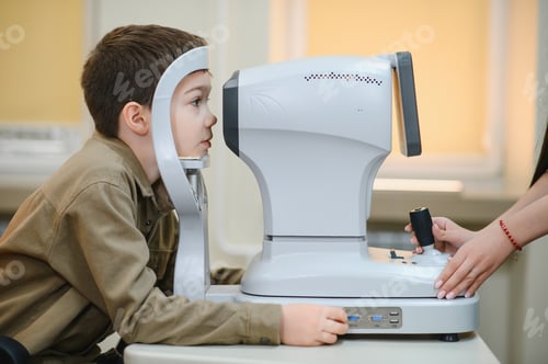 Preview: Boy undergoing eyesight examination with autorefractor keratometer in ophthalmology clinic