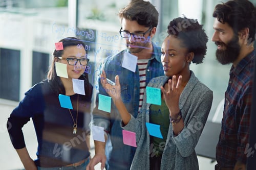 Preview: Mapping it all out. Shot of a group creative businesspeople working on a glass wall in the office.