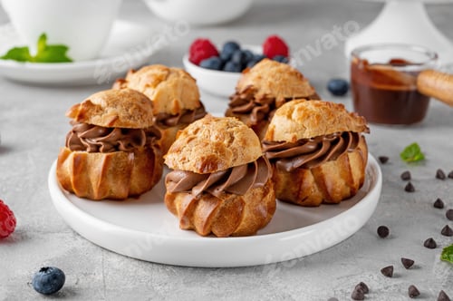 Preview: Profiteroles with chocolate cream, fresh berries and chocolate glazed on a plate