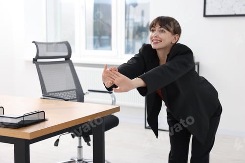 Preview: Young businesswoman doing stretching exercise in office