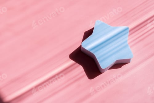 Preview: Blue cosmetic sponge in the shape of a star on a pink background with deep shadows. Beauty concept.