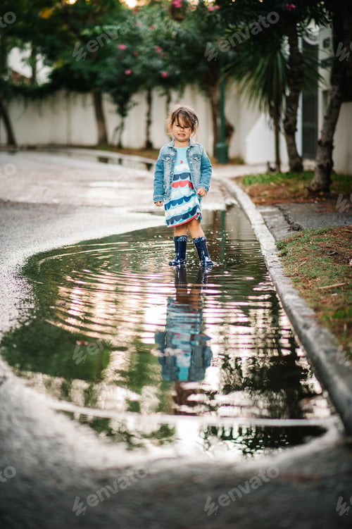 Preview: small girl playing with puddle in street