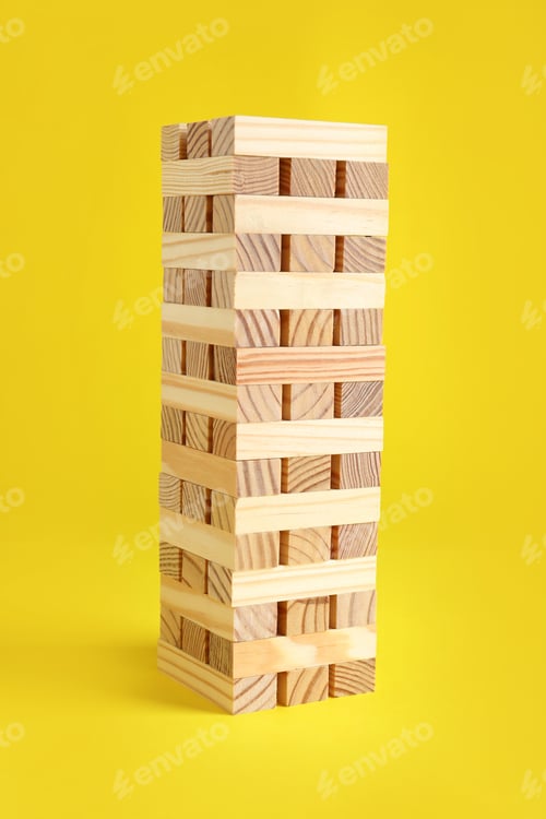 Preview: Mykolaiv, Ukraine - September 08, 2021: Jenga tower made of wooden blocks on yellow background