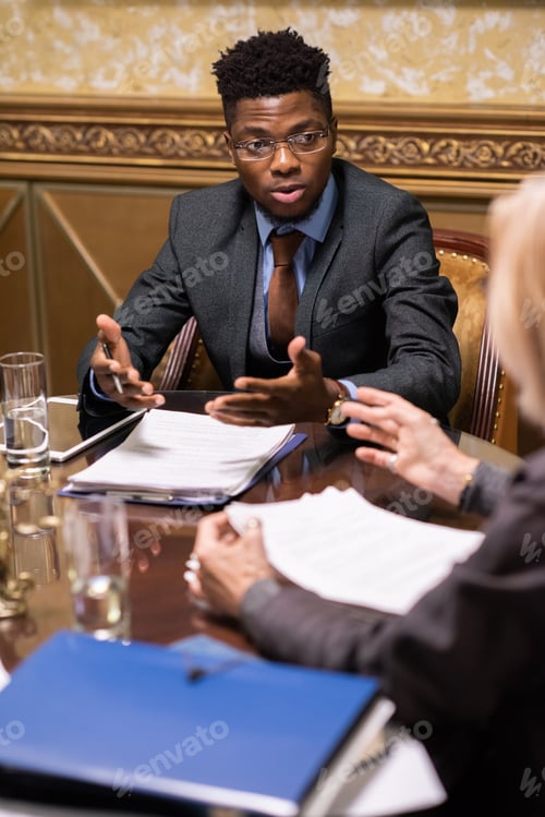 Preview: Young confident lawyer in formalwear having discussion with colleague