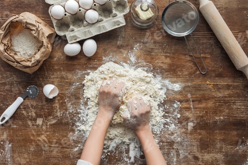 Preview: top view of female hands making dough on wooden table