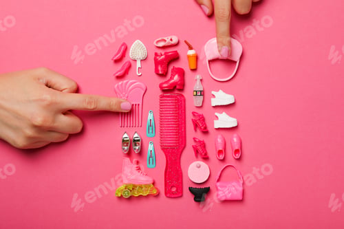 Preview: Doll accessories and female hands on pink background, top view