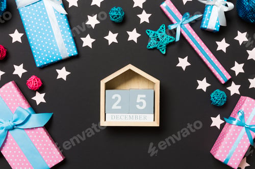 Preview: Top view of female hands holding calendar on black background. The twenty fifth