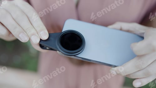 Preview: Close up of woman putting removable lens for smartphone on its camera. Action. Concept of