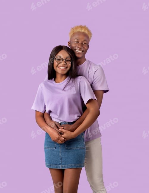 Preview: Cheerful African American guy hugging his beloved woman from behind, smiling and looking at camera