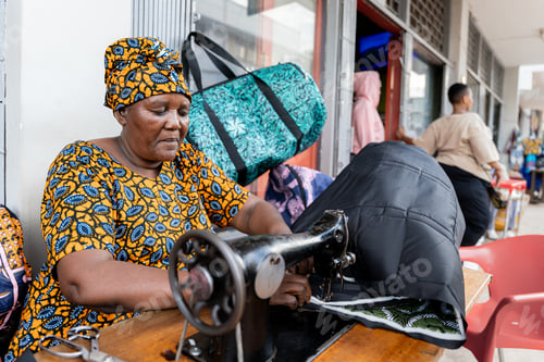 Preview: African woman with traditional clothes working sewing with a machine