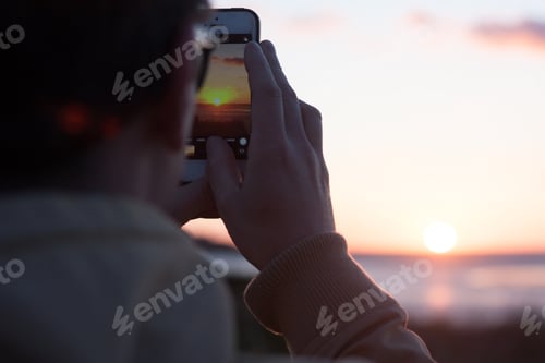 Preview: A man takes a picture of the sunset on his phone