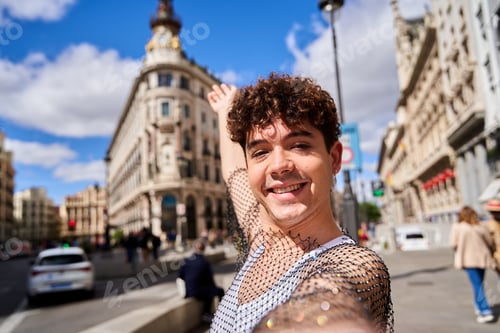 Preview: A man with curly hair is taking a selfie with his phone. He is smiling and he is enjoying himself