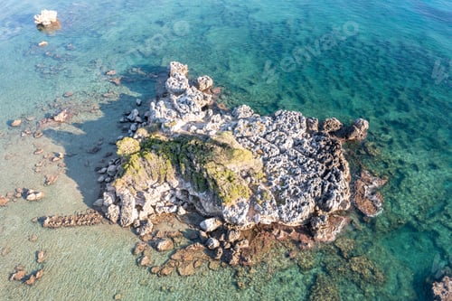 Preview: Aerial drone view of rocky formation with moss on it in blue Aegean sea.