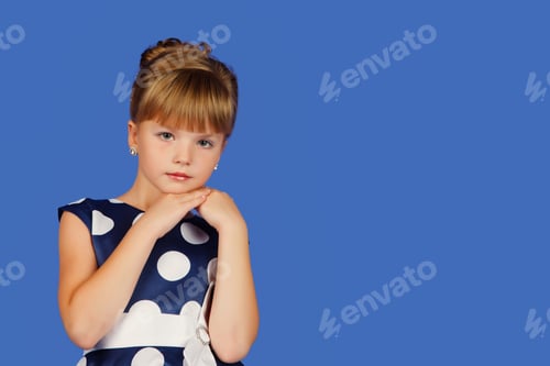Preview: Portrait of little graceful girl 8-9 year old in polka dot dress at isolated blue