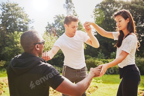 Preview: Man and woman holding hands with personal trainer balancing in park