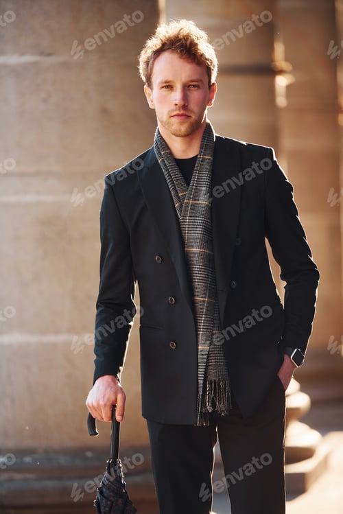 Preview: Holding umbrella. Elegant young man in formal classy clothes outdoors in the city
