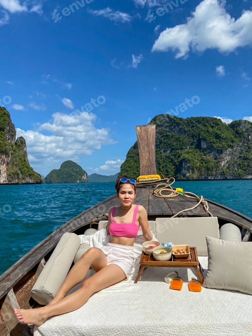 Preview: Woman tourist in private longtail boat trip to island with exotic food picnic, Krabi, Thailand.