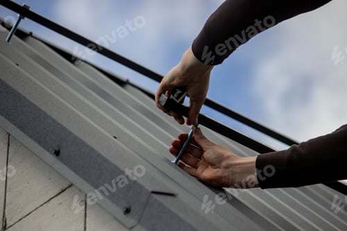 Preview: A man is installing solar panel mounts on the roof. Selective focus