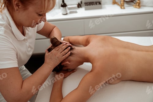 Preview: Female client receiving professional scalp massage in spa salon