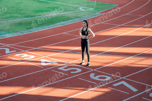Preview: Young sportswoman standing on running track preparing for race competition