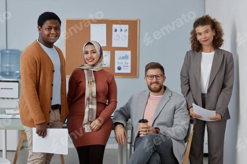 Preview: Group of young successful employees with documents standing in office