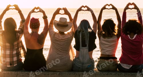 Preview: Love and meditation lifestyle concept - group of women looking at the sunset on the ocean