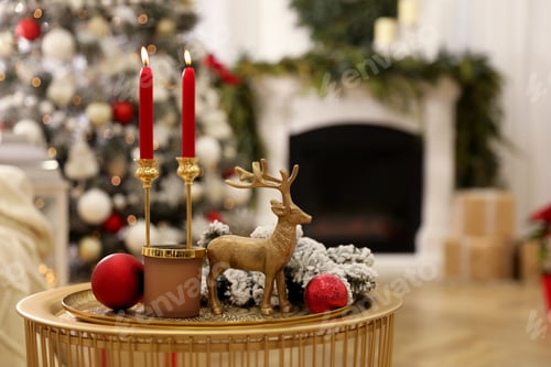 Preview: Christmas composition with decorative reindeer and candles on golden table in room, space for text